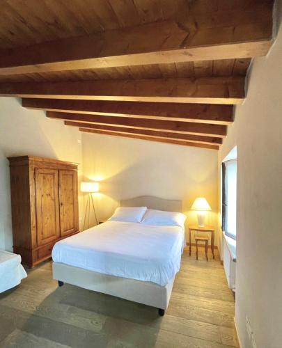 a bedroom with a white bed and a wooden ceiling at Ca' Malfer in Costermano sul Garda