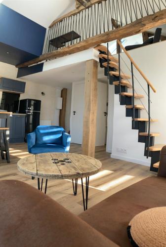 a living room with a spiral staircase and a table at Grange rénovée au calme entre Rennes et Saint Malo in Vignoc