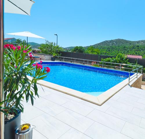 a swimming pool in the middle of a patio with flowers at Villa Salvia Mare in Bilice