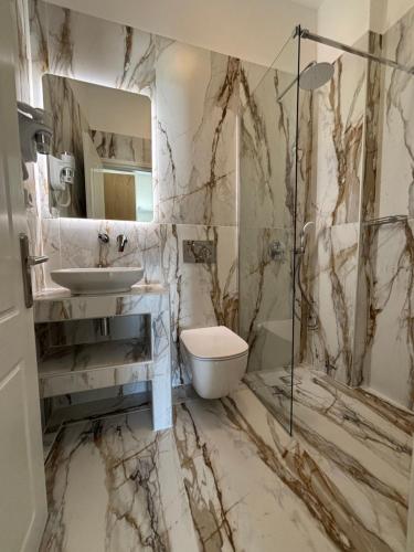 a marble bathroom with a sink and a toilet at Margarita Karidi in Apollonia
