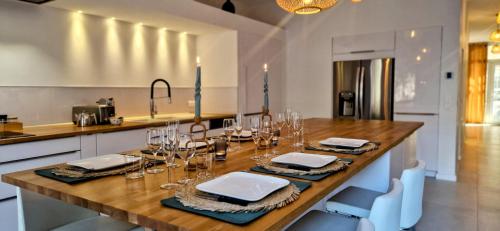 une cuisine avec une table en bois, des assiettes et des verres dans l'établissement ESPRIT LOFT, Appartement d'Exception, 3 chambres, Jardin au Centre Ville, Climatisation, à Sète