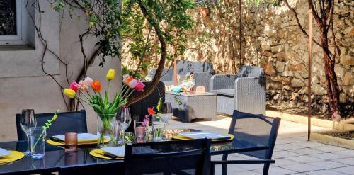 - une table noire avec des chaises et des fleurs sur la terrasse dans l'établissement ESPRIT LOFT, Appartement d'Exception, 3 chambres, Jardin au Centre Ville, Climatisation, à Sète