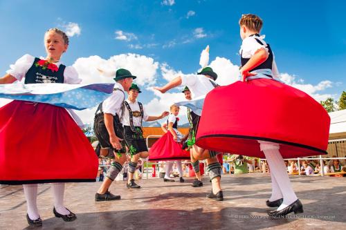 a group of children dancing in dresses in a parade at Ferienwohnung Ferienglück in Krün