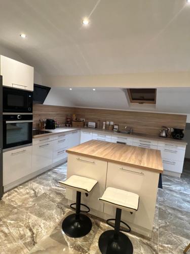 une cuisine avec des armoires blanches et un comptoir avec des tabourets dans l'établissement Appart Magnifique 2 chambres, à Molinges