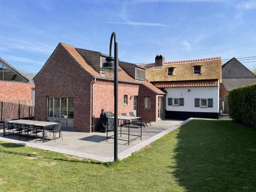 a house with a table and chairs in a yard at ANHOVE in Maarkedal