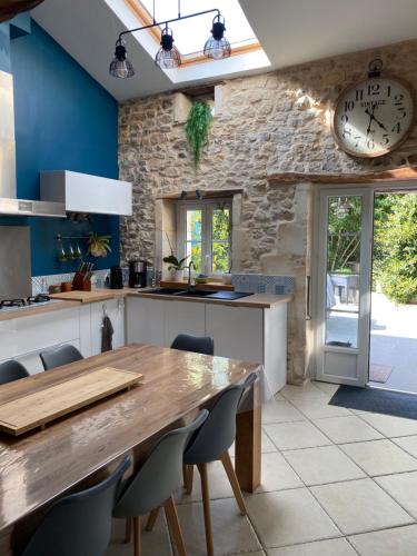 une cuisine avec une table en bois et une horloge au mur dans l'établissement Les 5 timbres, à Montpellier-de-Médillan