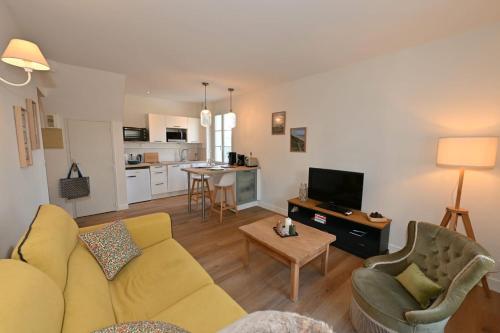 un salon avec un canapé jaune et une table dans l'établissement La marinière au 5, à Trouville-sur-Mer