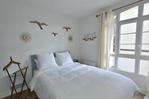 une chambre blanche avec un lit et une fenêtre dans l'établissement La marinière au 5, à Trouville-sur-Mer