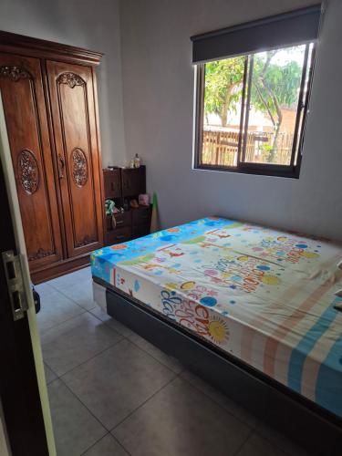 a bedroom with a bed with a comforter and a window at Wima homestay batu in Batu