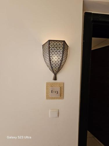 a lamp on a wall next to a bed at E13 Samarah Resort Apartment in Sowayma