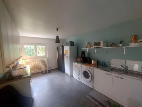 une cuisine avec un réfrigérateur et une machine à laver dans l'établissement Chambre d'hôte, à Bon-Encontre
