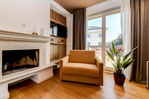 a living room with a fireplace and a chair and a window at Hotel Arya by Mauro in Sirmione
