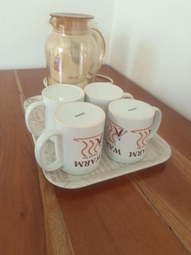a tray with four coffee cups and a glass jar at WARM Tourist Inn in Badian