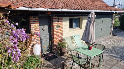 a small house with a table and a umbrella at Studio Malow in Arques
