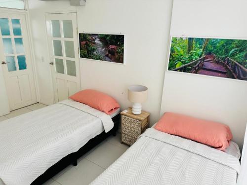 a bedroom with two beds and a lamp on a table at Casa Pura Vida in Puntarenas