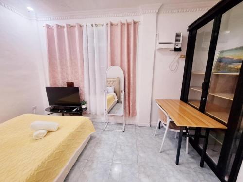 a bedroom with a bed and a desk and a television at N2 Studio Room Apartment Transient House Ground Floor walking distance to Abreeza Mall, USEP, SM Lanang in Davao City
