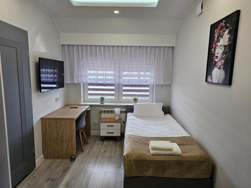 a small bedroom with a bed and a desk at Pensjonat-ek pod Jaworem in Hajnówka
