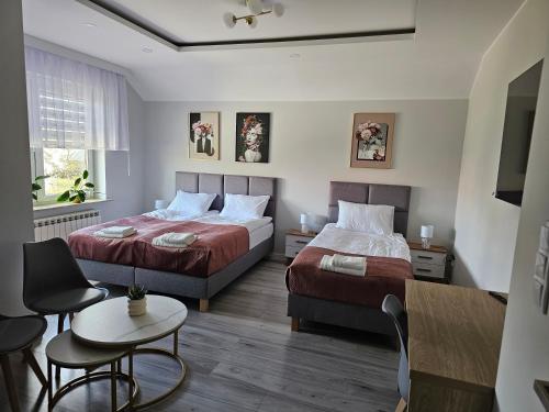 a bedroom with two beds and a table and chairs at Pensjonat-ek pod Jaworem in Hajnówka