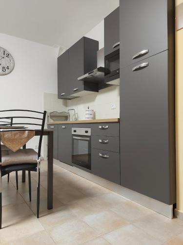 a kitchen with grey cabinets and a table and a table and chair at Vera Alloggio Alessandria nr2 in Alessandria