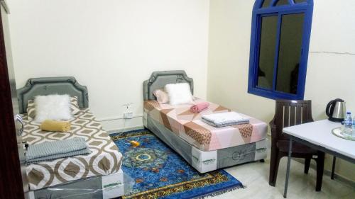 a bedroom with two beds and a table and a mirror at SALEM House Hostel Nizwa in Nizwa