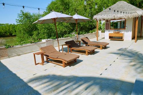 a group of lounge chairs and umbrellas on a patio at Hôtel Baobab Café in Morondava