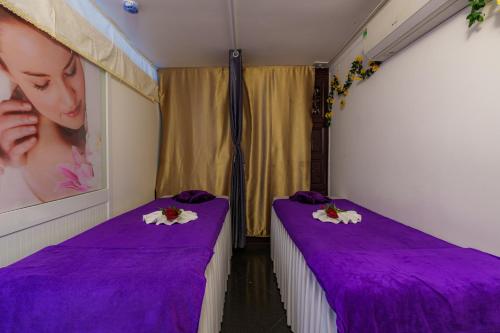 two beds in a room with purple sheets at Salute Saigon Hotel and Spa in Ho Chi Minh City
