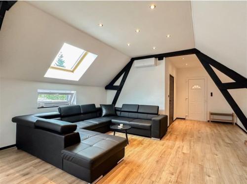 - un salon avec un canapé noir et une lucarne dans l'établissement Ô13 Loft privatif sauna balnéothérapie à 30min de Pairi Daiza, à Quiévrechain