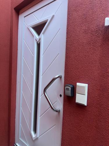 a white door with a handle on a red wall at Holiday Apartment in Mörfelden-Walldorf in Mörfelden-Walldorf