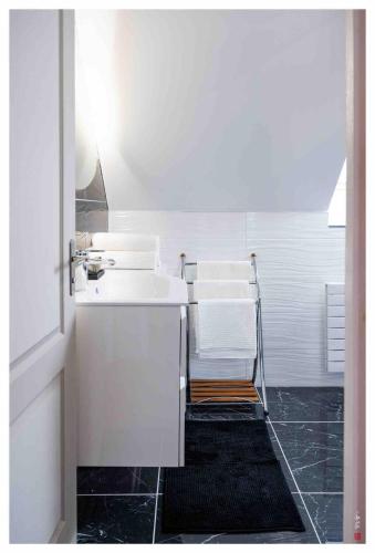 La salle de bains blanche est pourvue d'un lavabo et de serviettes. dans l'établissement Charmante maison entre Paris et Disney, à Courtry