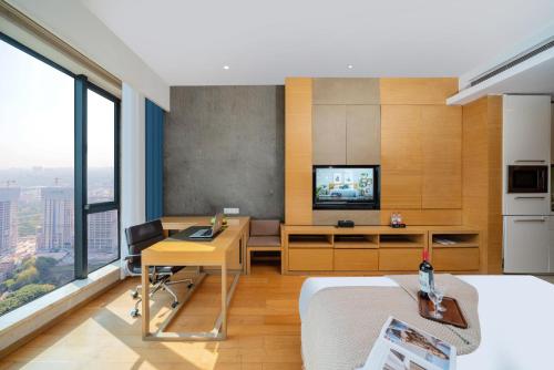 a bedroom with a desk and a tv in a room at Guangzhou Canton Fair Jufeng Administrative Hotel Poly World Trade Center Branch in Guangzhou