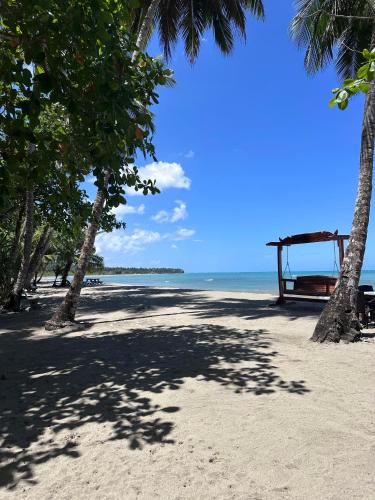 a beach with palm trees and a bench on the sand at Playa Paraiso en Magante in La Yagua