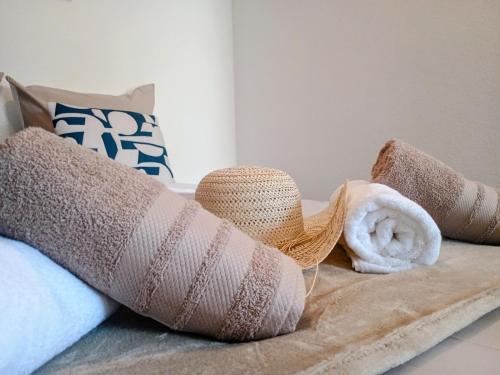 ein Stapel Handtücher und Hüte auf einem Bett in der Unterkunft Studio Beau Soleil in LʼIsle-sur-la-Sorgue