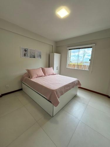 a bedroom with a bed with pink sheets and a window at villa privilege ap 01 in Marau