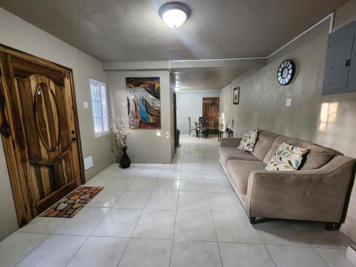 a living room with a couch and a clock on the wall at Portland Jamaica! Green and Lush! Volcano and Falls Yes! in Lenox