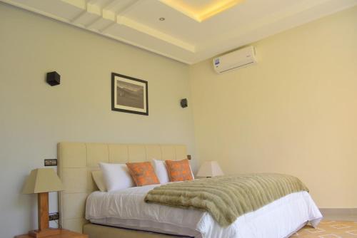 a bedroom with a large bed with orange pillows at Villa Essalam Marrakech in Marrakech