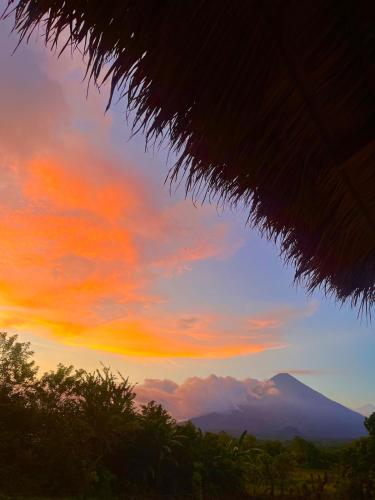 a sunset with a mountain in the background at Finca Aisa -Boutique bungalows in Ometepe island in Santa Cruz