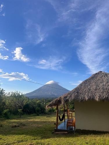 a hut with a hammock and a mountain in the background at Finca Aisa -Boutique bungalows in Ometepe island in Santa Cruz
