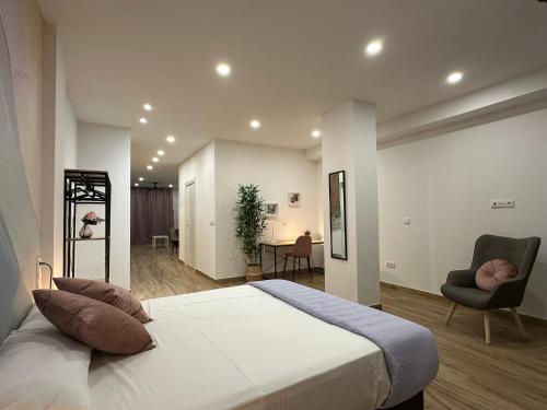 Un dormitorio con una gran cama blanca y una silla. en La fonda de Olympia, en Valencia