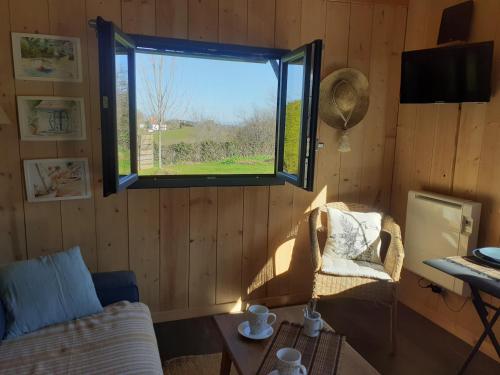 Cette chambre dispose d'une fenêtre, d'un canapé et d'une table. dans l'établissement Maison Hamak, à Urrugne