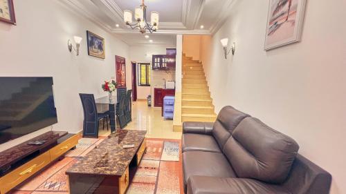 a living room with a couch and a television and stairs at SERENITY Flat3 in Pointe-Noire