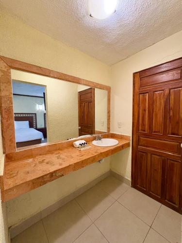 a bathroom with a sink and a mirror and a bed at Suites Cancun Center in Cancún