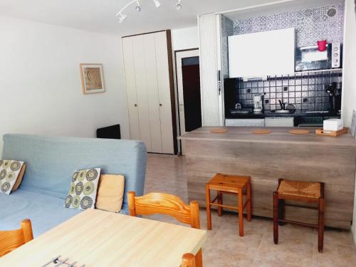 a living room with a blue couch and a table at Appartement Cabine - Résidence du PARC - Quartier du couchant - Proche de la mer in La Grande-Motte