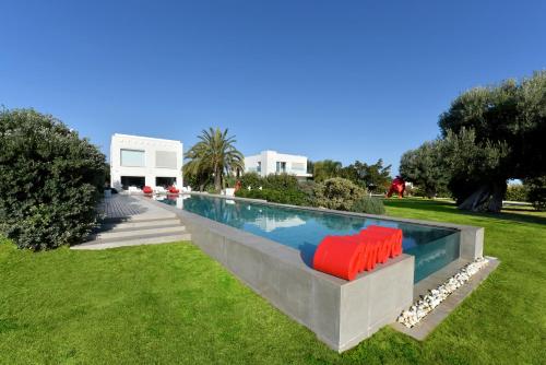 a swimming pool with red chairs in the grass at Villa VINNER - Monopoli in Monopoli