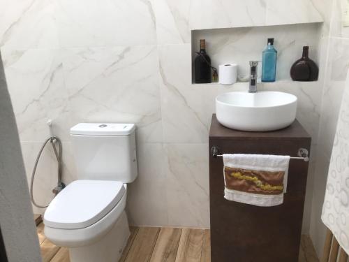 a white bathroom with a toilet and a sink at Granados in Asuncion