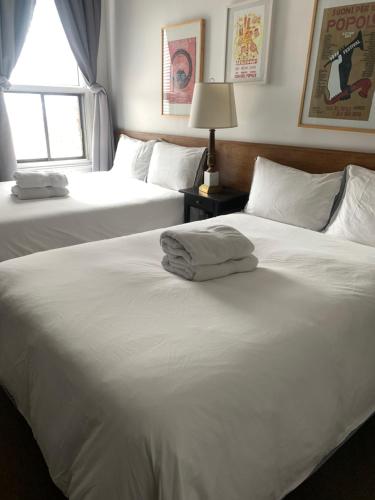 two white beds in a bedroom with a window at Pensione Popolo in Montréal