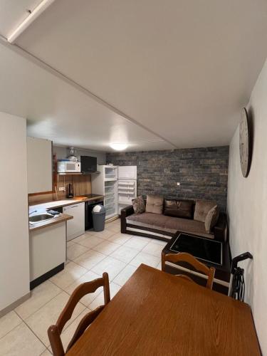 Il dispose d'une cuisine et d'un salon avec un canapé et une table. dans l'établissement Appartement en rez de jardin, à La Roche-de-Rame