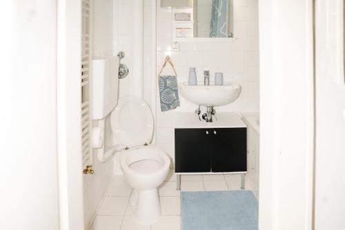 a white bathroom with a toilet and a sink at Sunny Maritime Apartment near Hannover central station in Hannover