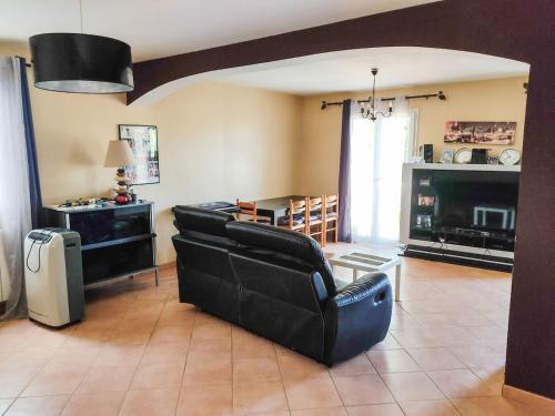 Elle comprend un salon doté d'un mobilier en cuir noir et d'une cheminée. dans l'établissement Maison 120m2 terrain de 700m2 clôturé, à Mirabeau