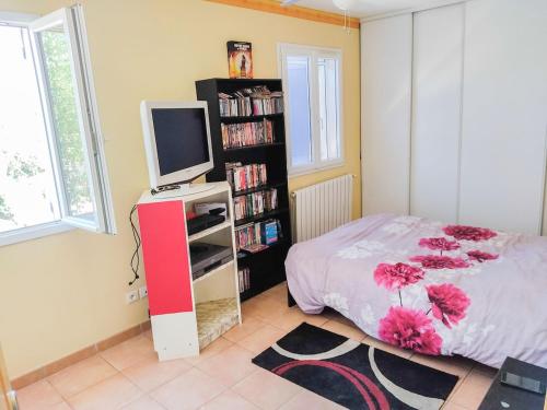 - une chambre avec un lit, une télévision et une étagère dans l'établissement Maison 120m2 terrain de 700m2 clôturé, à Mirabeau
