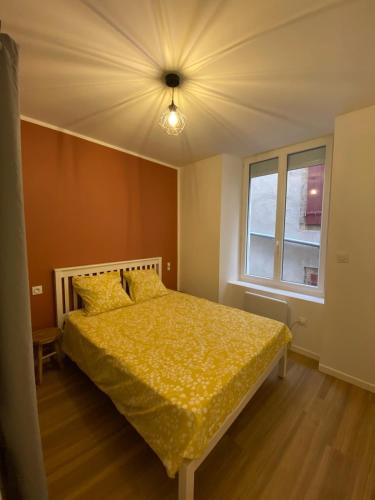 - une chambre avec un lit doté d'une couette jaune et d'une fenêtre dans l'établissement Appartement T3 rénové, à Millau